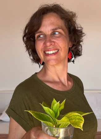 Evelyn Wagner lächelt im Profil und hält eine Pflanze im Wasserglas